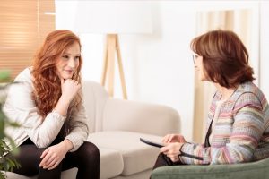 Woman doctor talking to patient sitting on a couch.