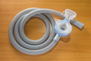 A CPAP mask and tube on a wood background