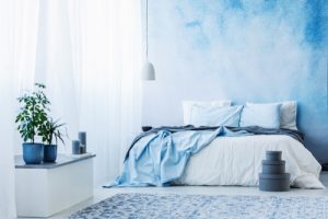 A bedroom with a bed in front of a blue and white wall