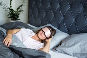 A woman sleeping in bed wearing an eye mask