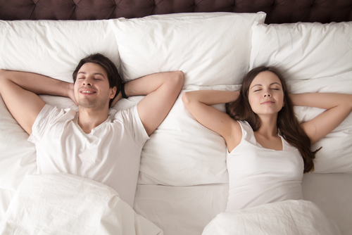 A man and woman sleeping on a mattress