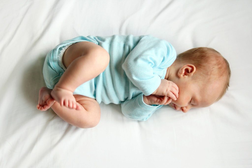 Baby sleeping peacefully on side in a flexed position