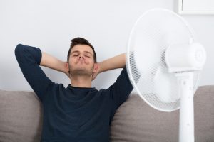 man sleeping in front of a fan