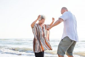 A couple dances on the beach because they're managing their sleep apnea while traveling.